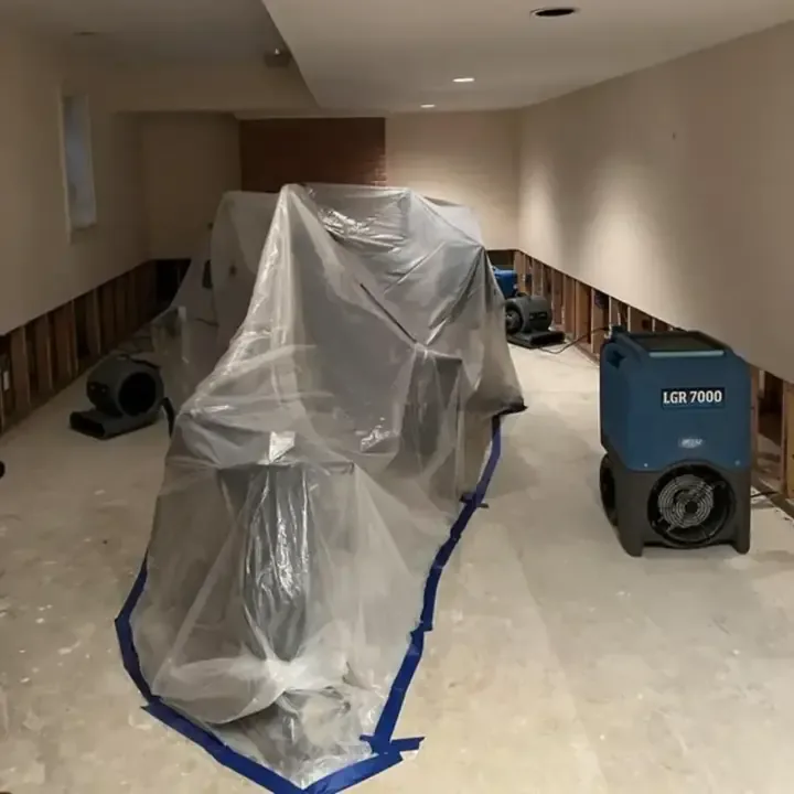 Containment sheeting and a dehumidifier beside opened lower walls