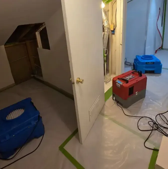 Dehumidifier and air movers drying a hallway and a closet under the stairs