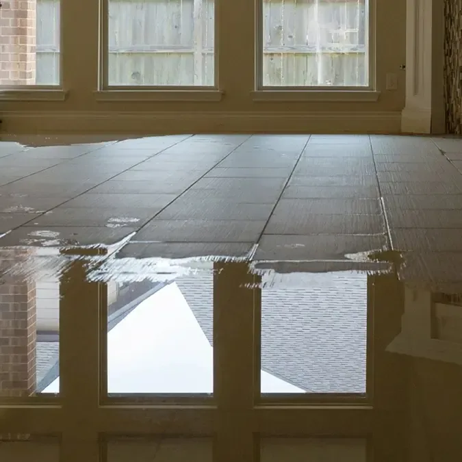 Standing water reflects the windows across a tiled interior floor before extraction begins.